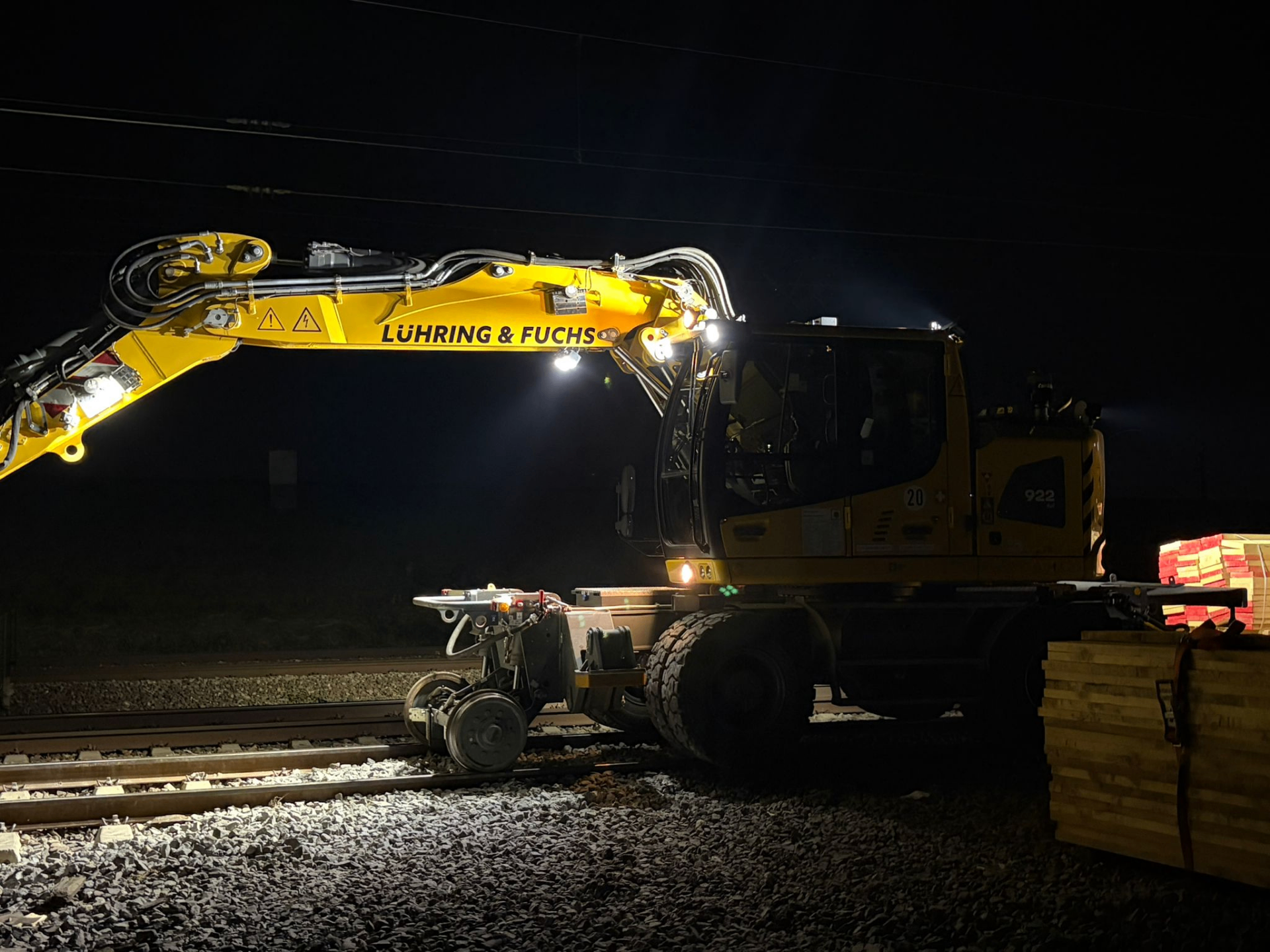 Liebherr-Zweiwegebagger bei Nachtarbeit auf der Schiene